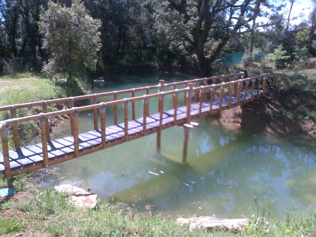 Puente artesanal de caña de bambú guadua con uniones de cuerda natural en jardín exterior