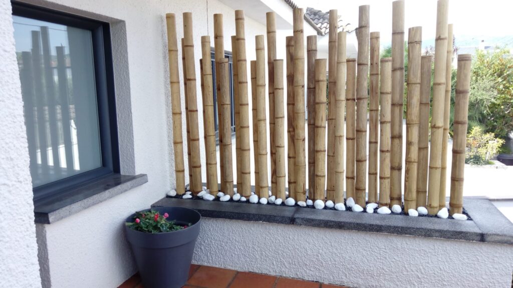 Biombo decorativo de cañas de bambú en jardinera para separar la entrada de una casa moderna