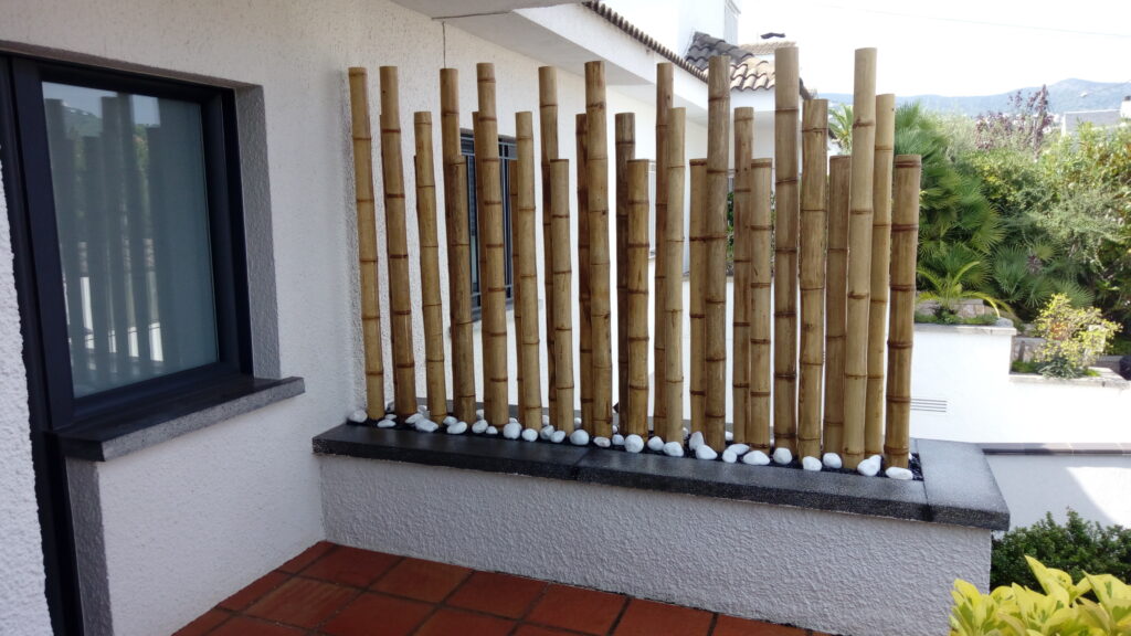 Biombo decorativo de cañas de bambú en jardinera para separar la entrada de una casa moderna