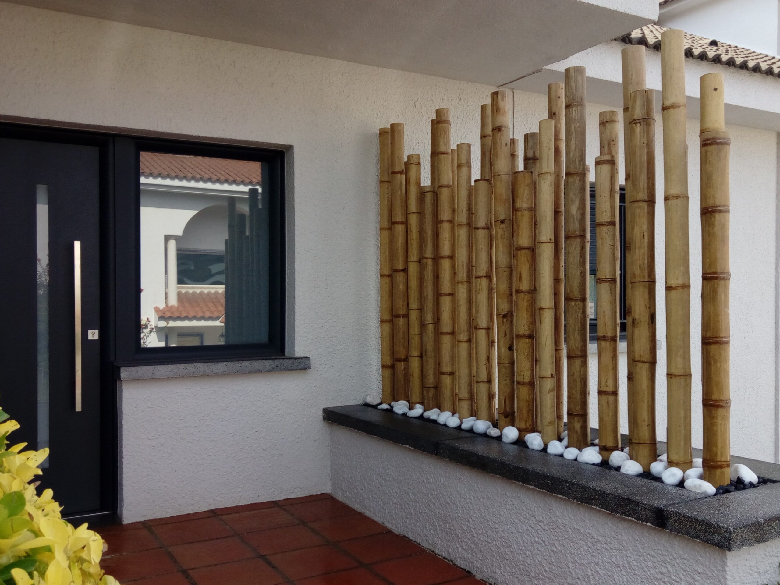 Biombo decorativo de cañas de bambú en jardinera para separar la entrada de una casa moderna
